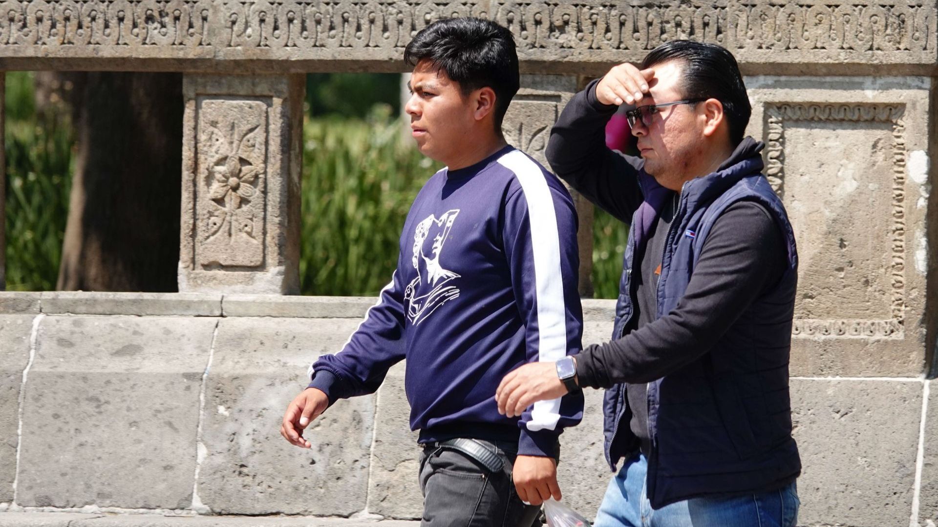 Un hombre y un niño caminan bajo el sol en la CDMX.